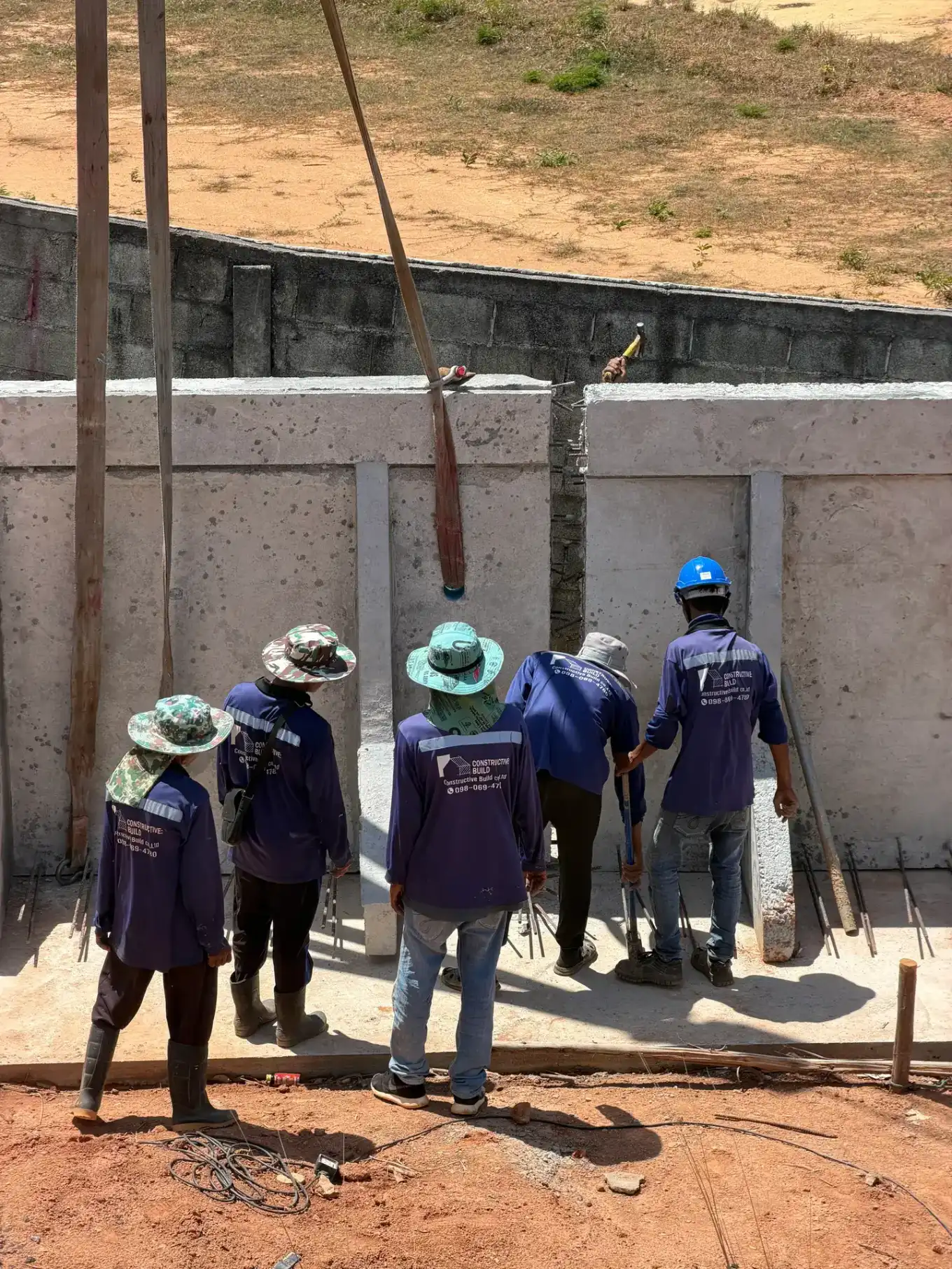 The Constructive Build site crew in branded uniforms working on precast villa walls at KĀHLĪ Phuket